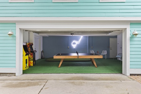 The garage game room features a full-size ping pong table, putting green and two standup arcade games.