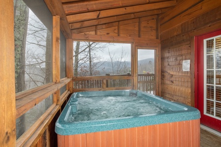 Hot tub on a screened in porch at Alpine Romance, a 2 bedroom cabin rental located in Pigeon Forge