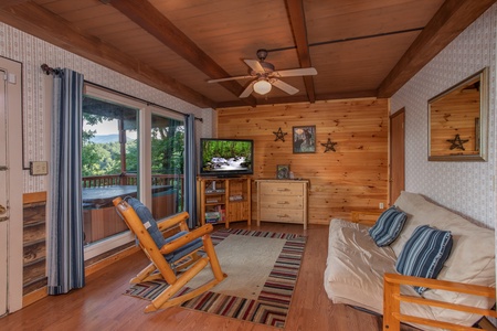 Game room with a futon, wood rocking chair, and TV at Bushwood Lodge, a 3-bedroom cabin rental located in Gatlinburg