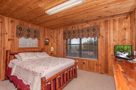 A queen-sized log bed and a television at Apple View, a 2 bedroom cabin rental located in Pigeon Forge
