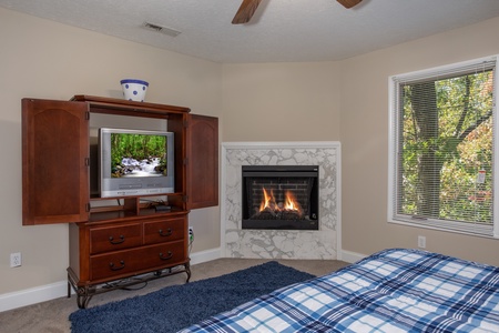 Bedroom with a TV, armoire, and fireplace at Into the Woods, a 3 bedroom cabin rental located in Pigeon Forge