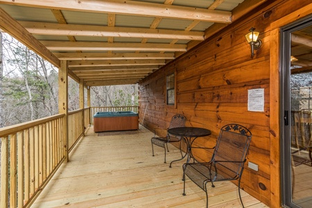 Bistro set for two and a hot tub on a covered deck at Boogie Bear, a 1-bedroom cabin rental located in Gatlinburg