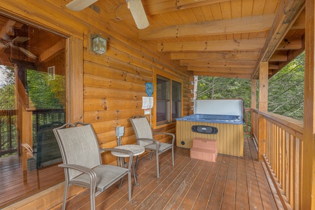 Two chairs, a table, and a hot tub on a covered deck at Cub's Crossing, a 3 bedroom cabin rental located in Gatlinburg