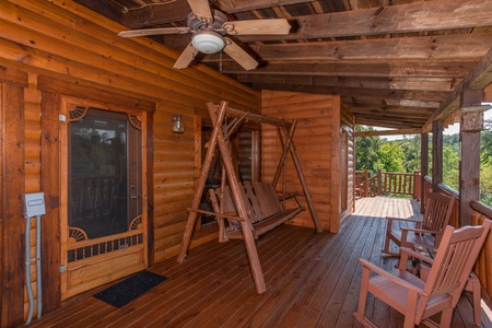 Log porch swing on a covered deck at Cabin Fever, a 4-bedroom cabin rental located in Pigeon Forge