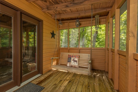 Porch swing on a screened in porch at Magic Moments, a 2 bedroom cabin rental located in Pigeon Forge
