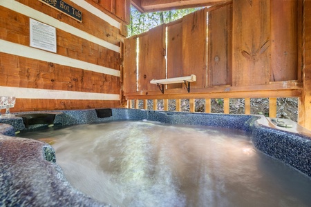 Hot tub on a covered deck with privacy fence at Bearfoot Crossing, a 1-bedroom cabin rental located in Pigeon Forge