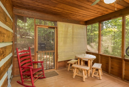 Screened in porch with a picnic table and rocking chair at Little Bear, a 1 bedroom cabin rental located in Pigeon Forge
