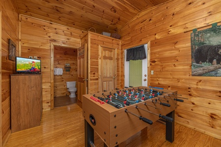 Foosball table, dresser, and TV in a bedroom at A Moment in Time, a 2 bedroom cabin rental located in Pigeon Forge