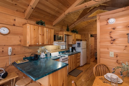 Looking into the kitchen with white appliances from the dining space at Boogie Bear, a 1-bedroom cabin rental located in Gatlinburg