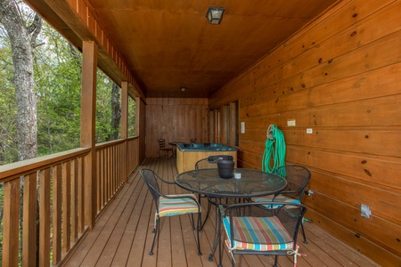 Dining area and hot tub on a covered porch at Hillside Haven, a 1 bedroom cabin rental located in Pigeon Forge