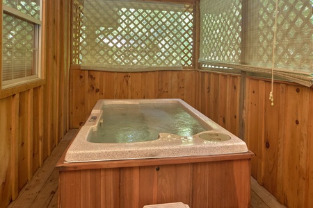 Hot tub on a covered deck with privacy fencing at Dream Catcher, a 1-bedroom cabin rental located in Pigeon Forge