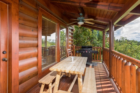 Picnic table with grill on a covered deck at Graceland, a 4-bedroom cabin rental located in Pigeon Forge