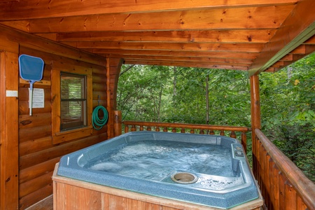 Hot tub on a covered deck surrounded by woods at Dreams Do Come True, a 1-bedroom cabin rental located in Pigeon Forge