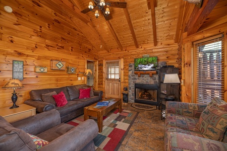 Fireplace, tv, and furniture in the living room at Gone Fishin', a 2-bedroom cabin rental located in Pigeon Forge