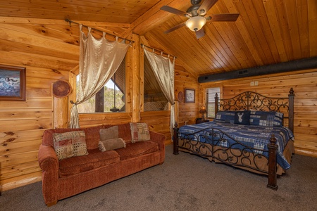 Loft bedroom with a king bed and sofa at God's Country, a 4 bedroom cabin rental located in Pigeon Forge