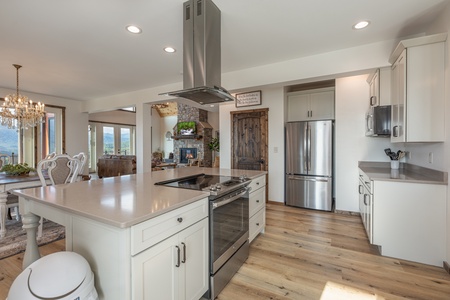 White kitchen with granite counters, stainless appliances, and adjacent dining space at Mountain Celebration, a 4 bedroom cabin rental located in Gatlinburg