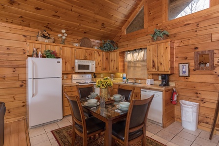 Dining space for four and kitchen with white appliances at Precious View, a 1 bedroom cabin rental located in Gatlinburg