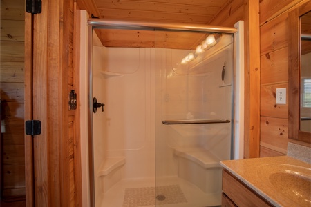 Bathroom with a walk-in shower with glass doors and built in seating at Cedar Creeks, a 2-bedroom cabin rental located near Douglas Lake