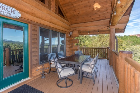 Outdoor dining set with seating for six on the covered deck at Great View Lodge, a 5-bedroom cabin rental located in Pigeon Forge