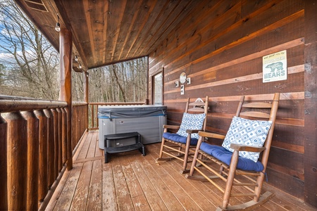 Hot tub and rocking chairs on a covered deck at Honey Bear Haven, a 1 bedroom cabin rental located in Pigeon Forge