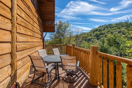 Dining space for four on an open deck at Great View Lodge, a 5-bedroom cabin rental located in Pigeon Forge