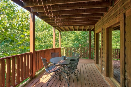 outdoor dining with space for four on a covered deck at angel's majestic view a 3 bedroom cabin rental located in pigeon forge