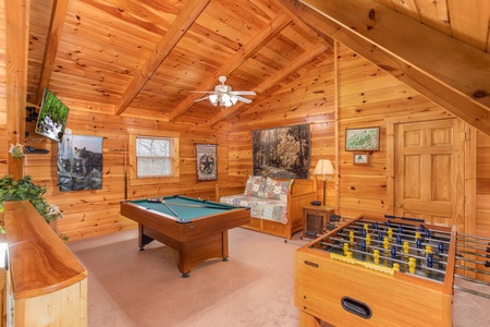Pool table, foosball table, TV, and trundle bed in the loft space at Enchanted Evening, a 1-bedroom cabin rental located in Pigeon Forge
