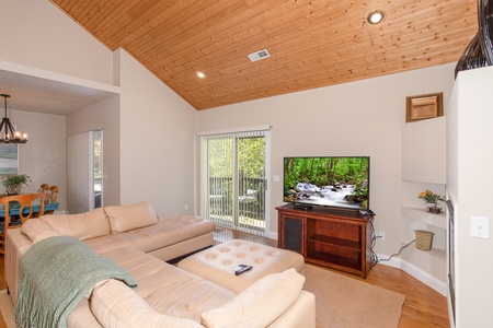 Living room with a large TV, sectional sofa, and deck access at Into the Woods, a 3 bedroom cabin rental located in Pigeon Forge