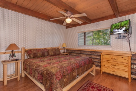 Bedroom with a king-sized log bed, dresser, and television at Bushwood Lodge, a 3-bedroom cabin rental located in Gatlinburg