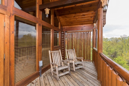 Covered deck with privacy fence and two rocking chairs at Howlin' in the Smokies, a 2 bedroom cabin rental located in Pigeon Forge