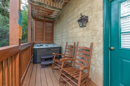 Rocking chairs and a hot tub on the covered deck at Southern Charm, a 2 bedroom cabin rental located in Pigeon Forge