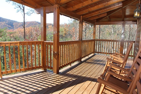 Rocking chairs on a covered deck overlooking the fall colors at Four Seasons Lodge, a 3-bedroom cabin rental located in Pigeon Forge