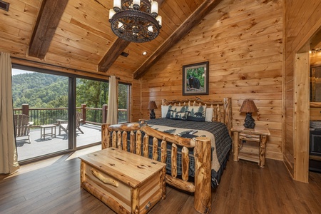 Bedroom with a king log bed, night stands, lamps, bench, and deck access at Black Bears & Biscuits Lodge, a 6 bedroom cabin rental located in Pigeon Forge
