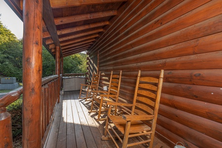 Rocking chairs on a covered deck at Family Getaway, a 4 bedroom cabin rental located in Pigeon Forge