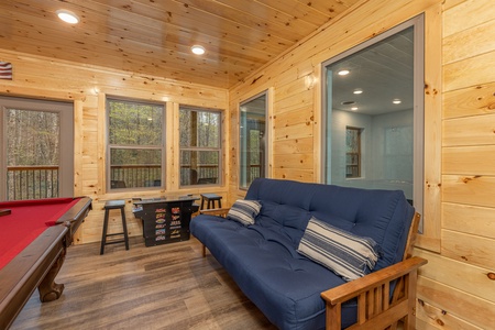 Futon and arcade game at Poolin Around, a 2 bedroom cabin rental located in Gatlinburg