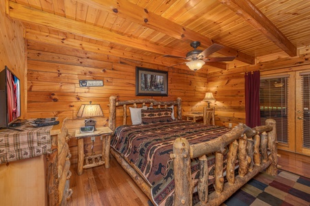 Bedroom with a log bed, two end tables, lamps, and a dresser with TV at Almost Bearadise, a 4 bedroom cabin rental located in Pigeon Forge