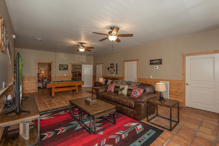 Sofa and TV in a living room with a pool table at Hawk's Heart Lodge, a 3 bedroom cabin rental located in Pigeon Forge
