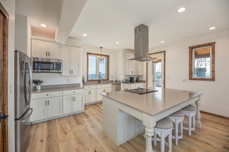 Kitchen with white cabinets, granite counters, and breakfast bar at Mountain Celebration, a 4 bedroom cabin rental located in Gatlinburg