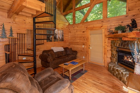 Living room with a fireplace and spiral staircase at Dreams Do Come True, a 1-bedroom cabin rental located in Pigeon Forge