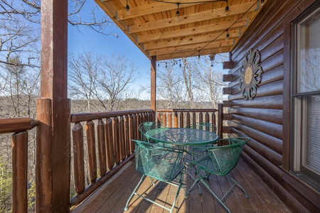 Dining table for four on a covered deck at Nascar Nation, a 2 bedroom cabin rental located in Pigeon Forge