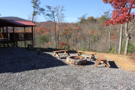 Looking at the fire pit and covered deck in the fall Four Seasons Lodge, a 3-bedroom cabin rental located in Pigeon Forge