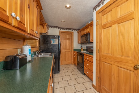 Galley kitchen with black appliances at Cub's Crossing, a 3 bedroom cabin rental located in Gatlinburg