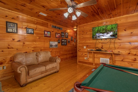 Loveseat, TV, and pool table in the game room at Firefly Ridge, a 2 bedroom cabin rental located in Pigeon Forge