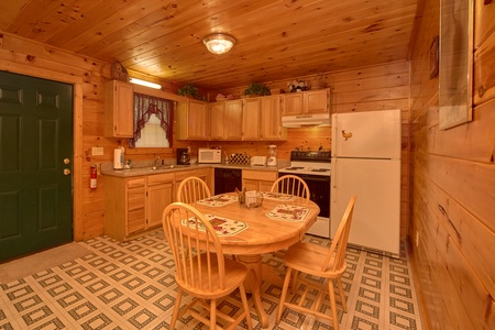 Dining table for four in the kitchen with white appliances at Dream Catcher, a 1-bedroom cabin rental located in Pigeon Forge