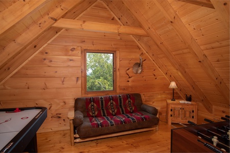 Air hockey table, futon, and foosball table in the game loft at Cedar Creeks, a 2-bedroom cabin rental located near Douglas Lake