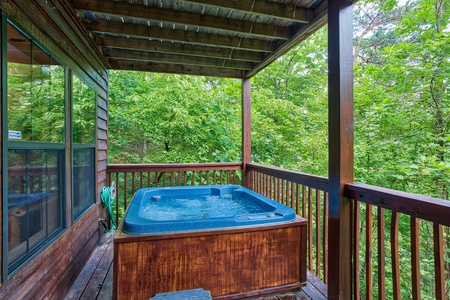 Hot tub on a covered porch in the woods at A View for You, a 1 bedroom cabin rental located in Pigeon Forge
