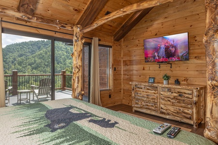 Dresser, TV, and deck access in a bedroom at Black Bears & Biscuits Lodge, a 6 bedroom cabin rental located in Pigeon Forge