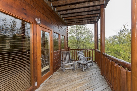 Two log rocking chairs on a covered deck at Howlin' in the Smokies, a 2 bedroom cabin rental located in Pigeon Forge