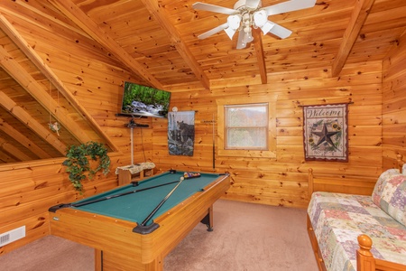 Trundle bed, pool table, and TV in the loft space at Enchanted Evening, a 1-bedroom cabin rental located in Pigeon Forge