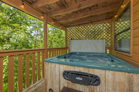 Hot tub on a covered porch at Magic Moments, a 2 bedroom cabin rental located in Pigeon Forge